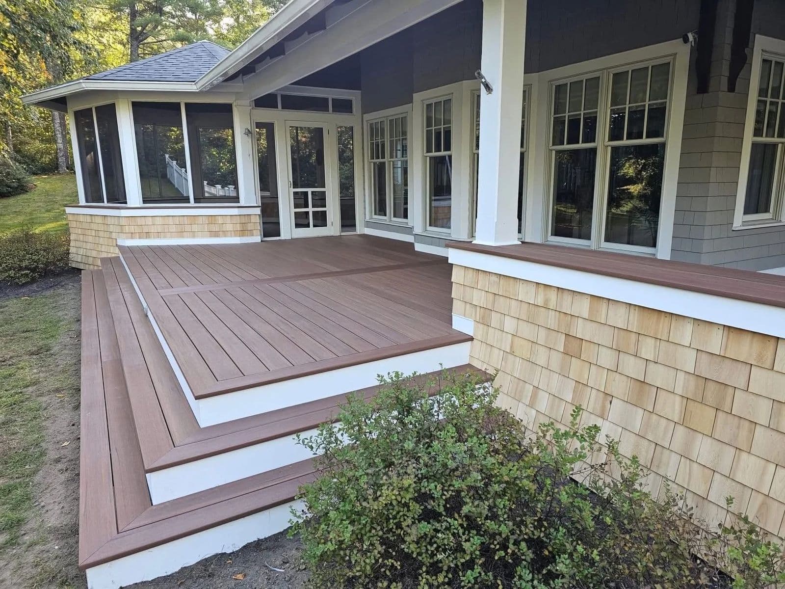 Composite decking on Cape Cod: a two-level brown composite deck with white trim on a cedar-shingled home in Barnstable